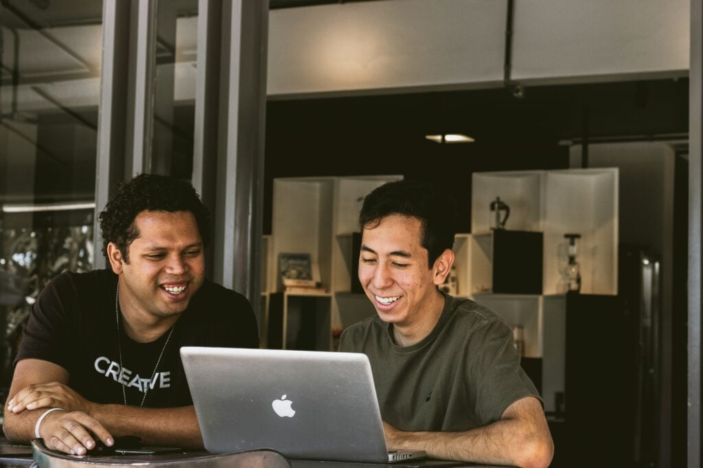 men smiling at Mac computer