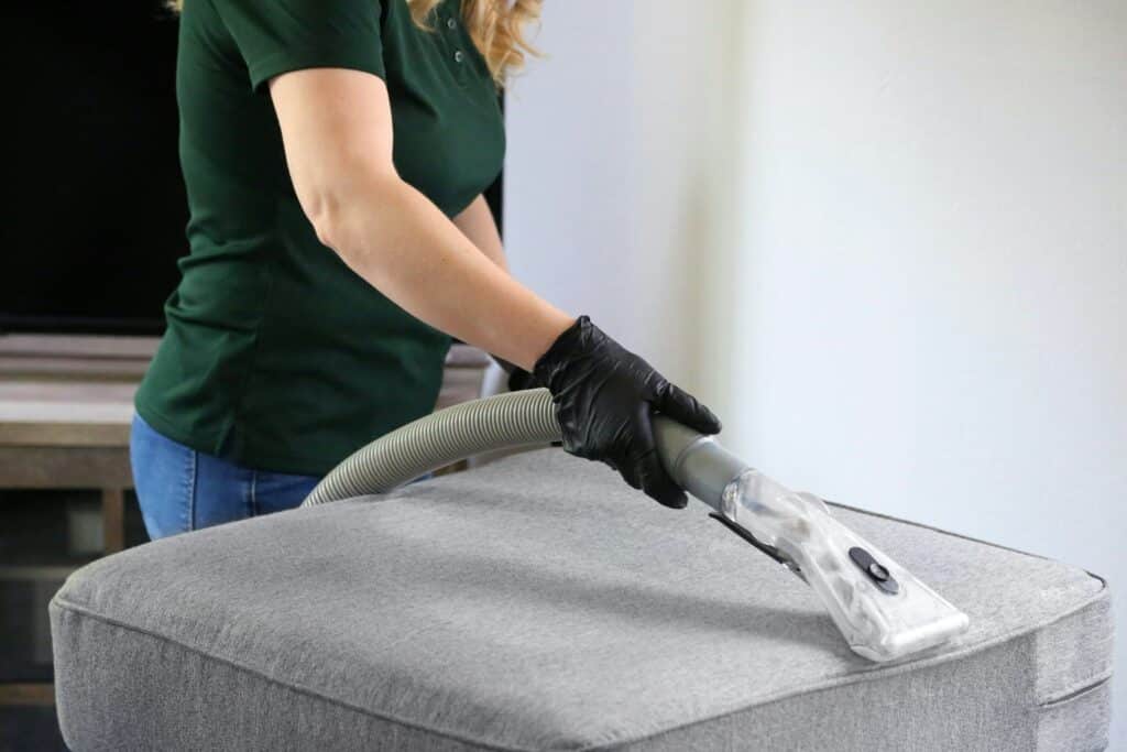 woman vacuuming sofa cushion 