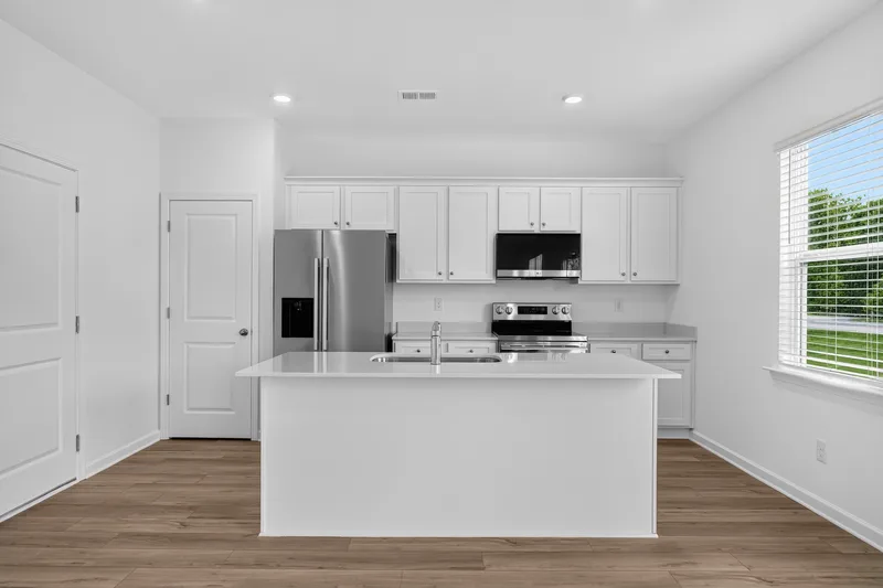 Bright white kitchen with island, stainless steel appliances, and hardwood floors