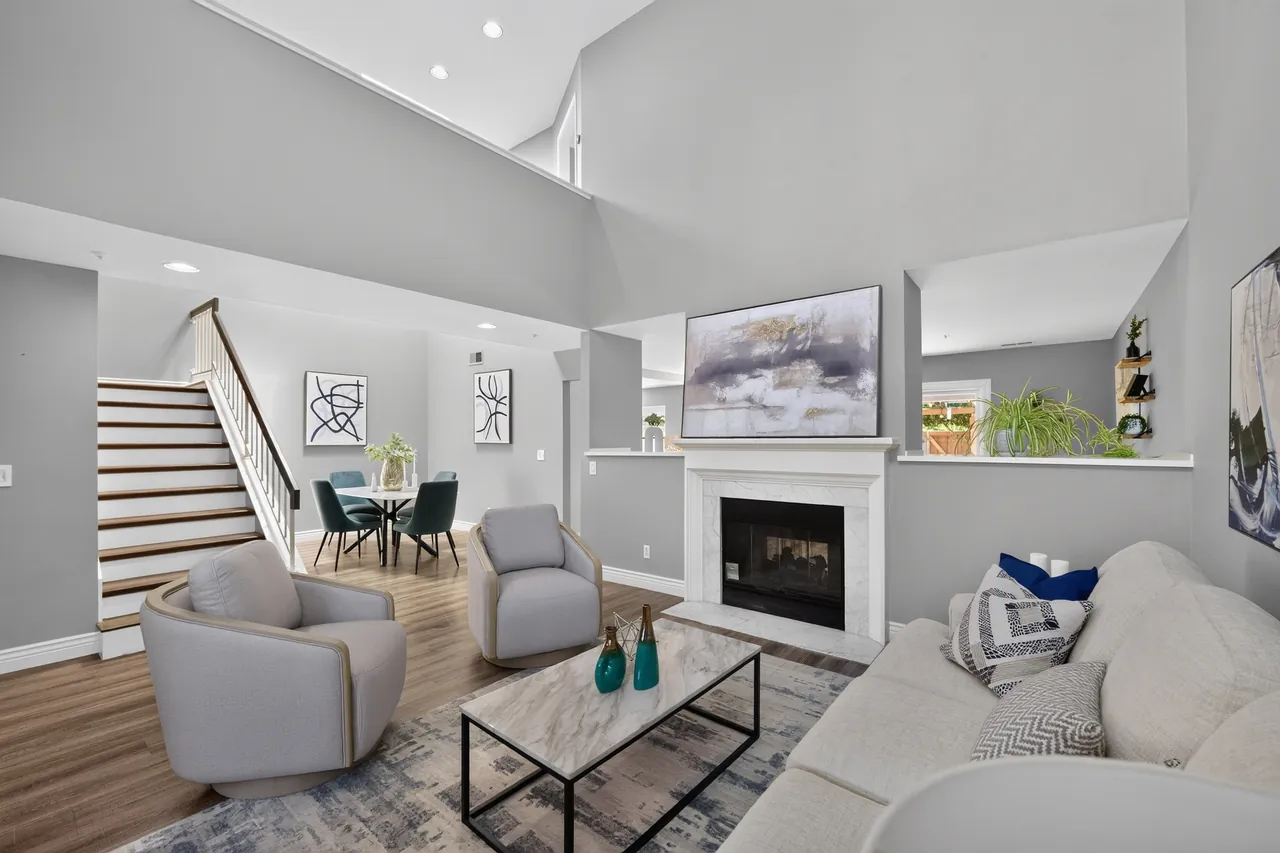 Staged two-story living room with a fireplace, sofa and dining area in a home prepared for sale