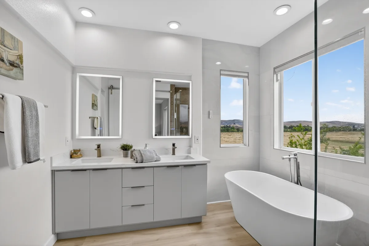 A renovated primary bathroom with a freestanding soaking tub and a view of open land, prepared before a listing photo shoot