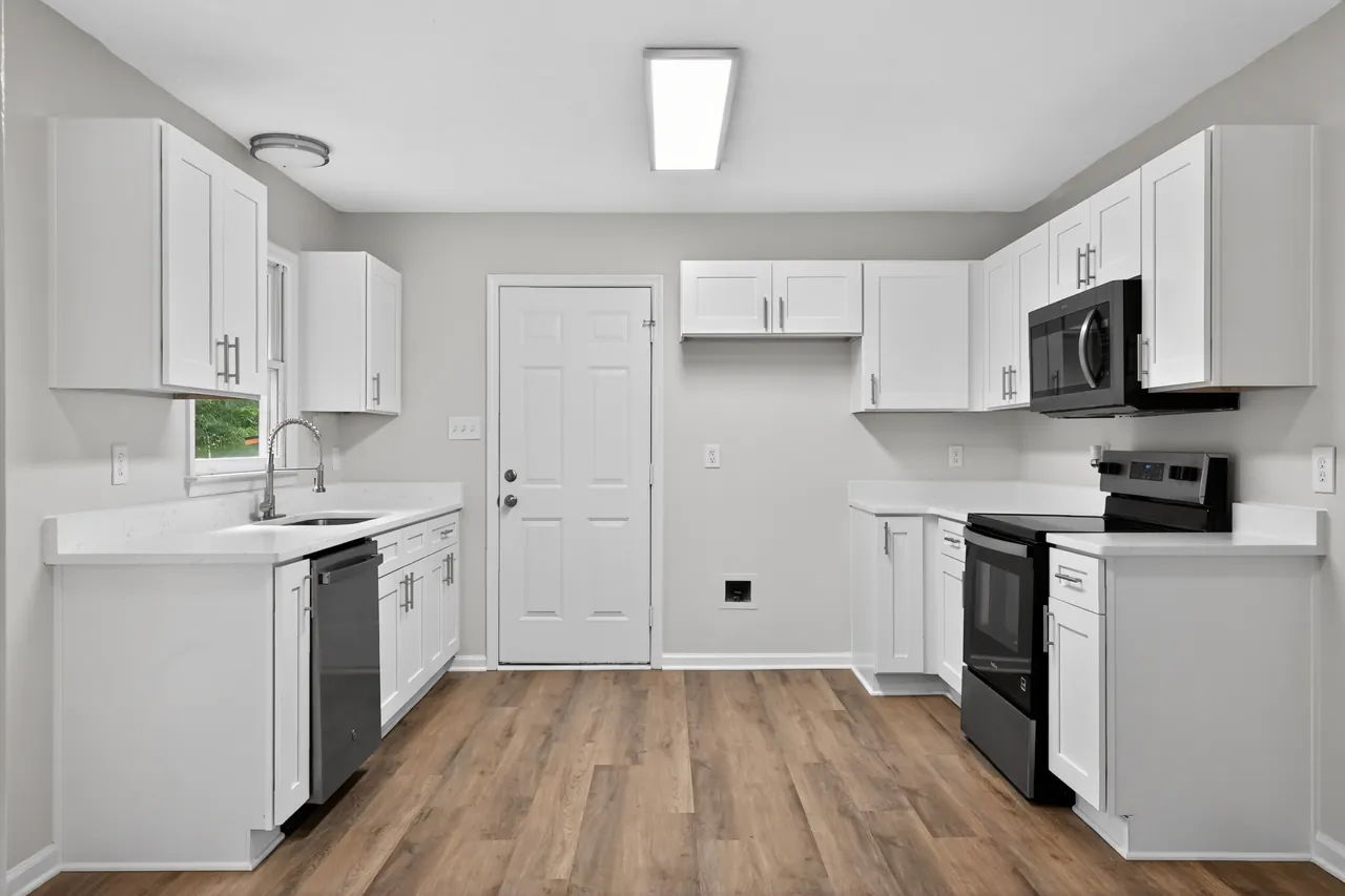 Freshly refreshed kitchen with white cabinets, quartz counters, stainless appliances and new vinyl plank flooring