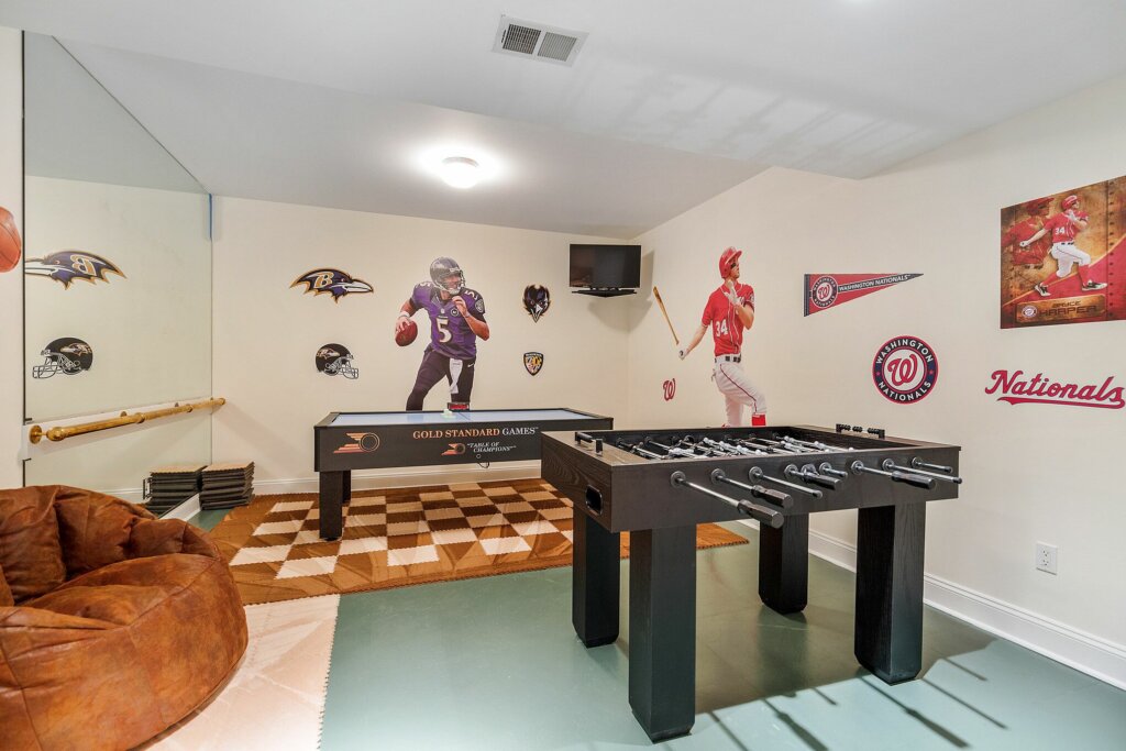 Indoor game room with table games and sports logos on the walls.