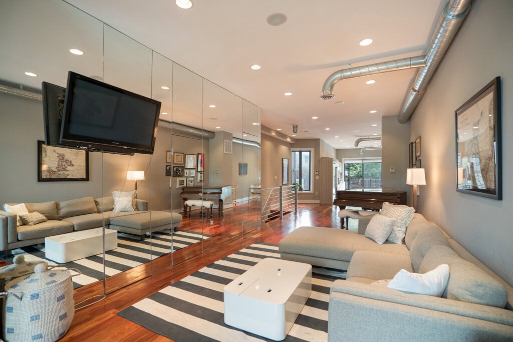 Living room with a wall mounted TV and mirrored walls. HomeJab.