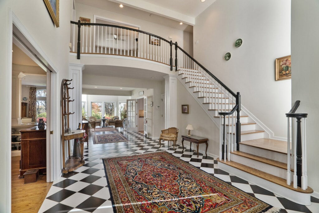 Beautiful foyer with checker board floor, white wall and staircase.