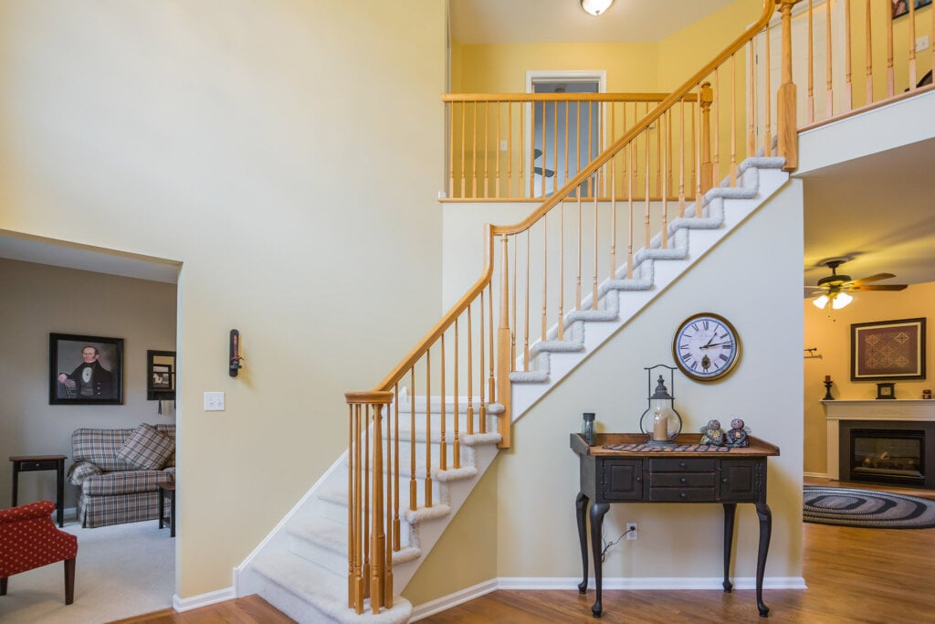 Foyer with white walls and stairs with wood handrails. 