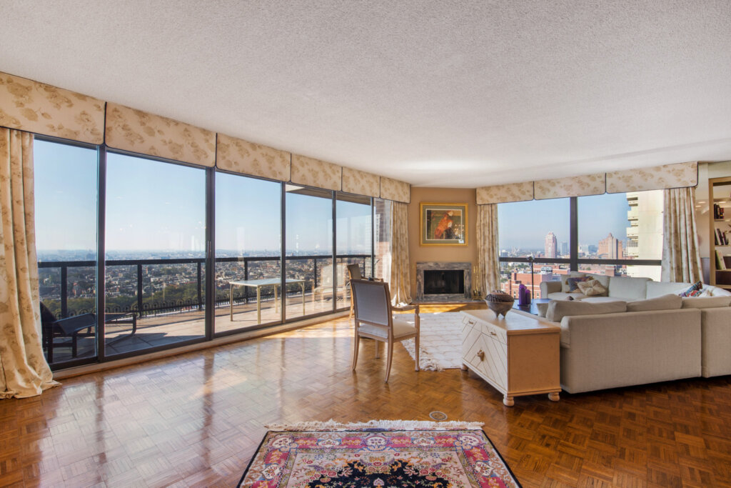 Large living room with wood floors and large picture windows over looking Philadelphia.