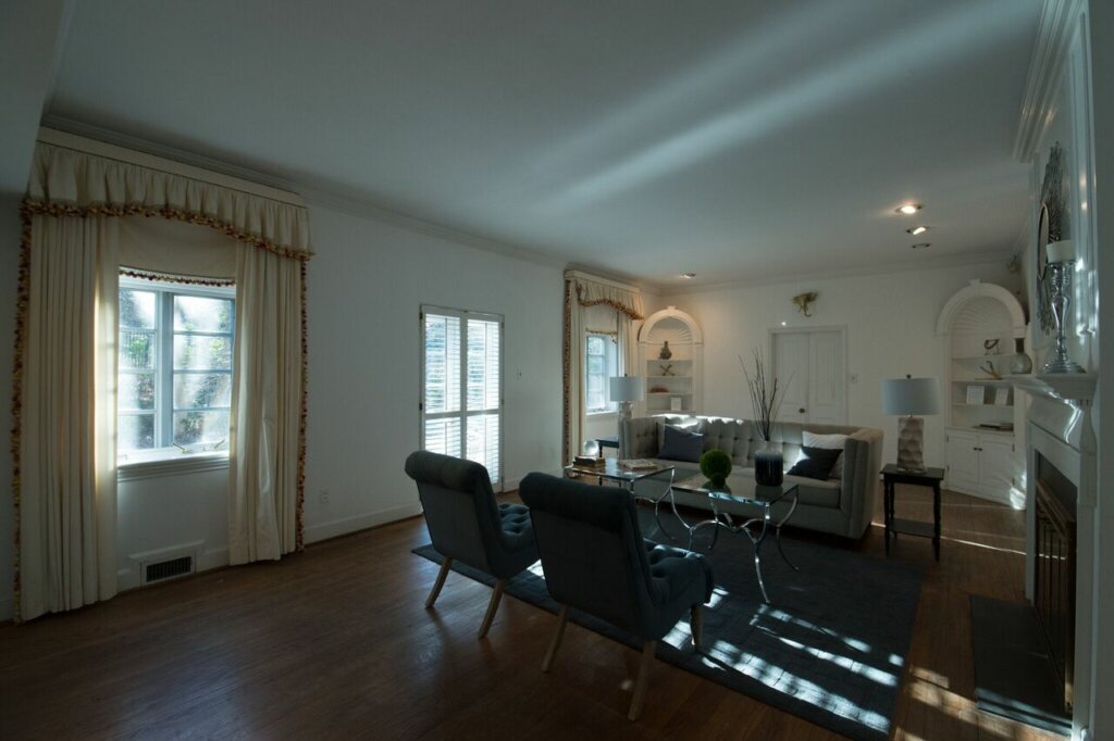 Large living room with a sofa and two chairs, white walls and wood floor.