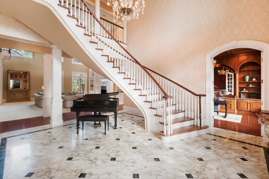 Large room showing a tall spiraling staircase, with a tiled floor and a piano.