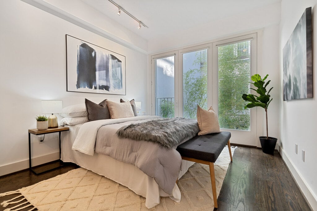 White bedroom with dark wood floors and wall art.