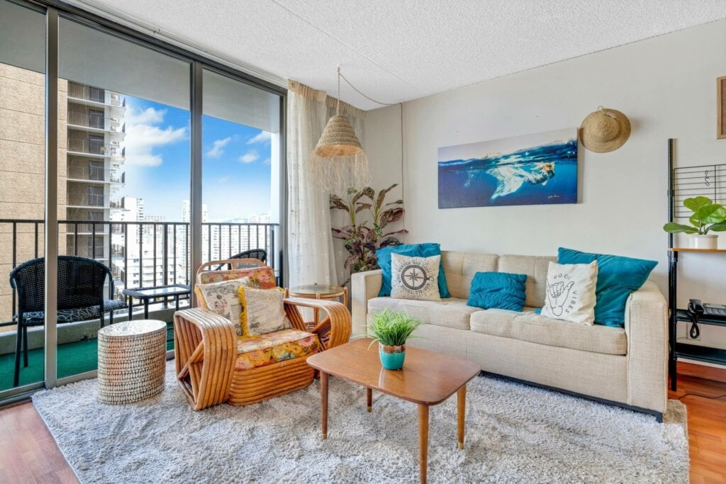 Bright HDR photo of a living room with a sofa, chair and sliding glass doors leading to the balcony.