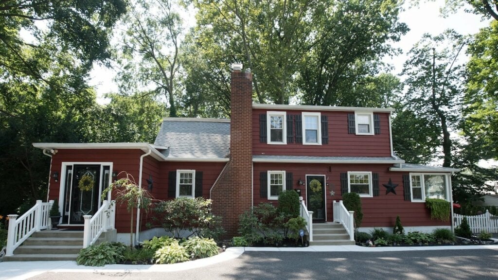 Large wide home with red siding and white trim taken on a cloudy day.