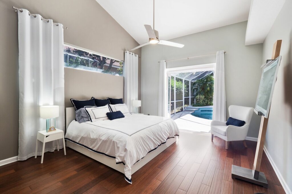 Bedroom with white wall, wood floor and white curtains, bed and furniture. - HomeJab