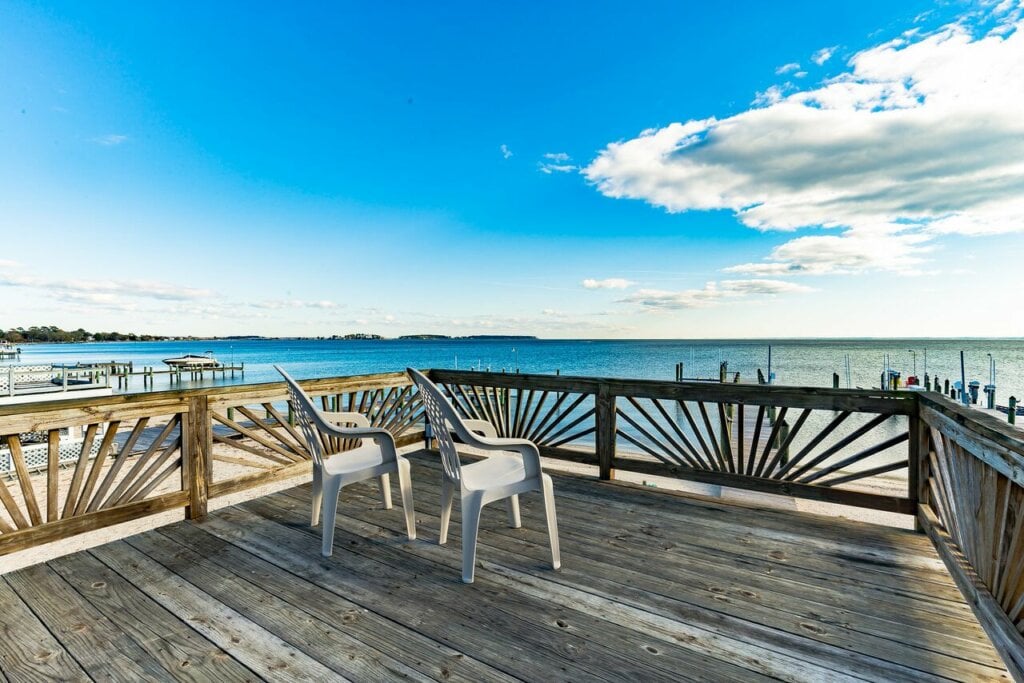 Outside wooden deck with two chairs over looking the ocean. - HomeJab