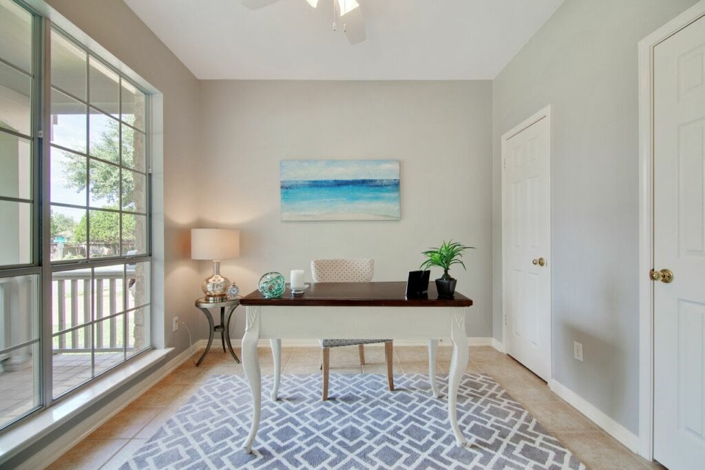 White room with a central desk and large window. - HomeJab