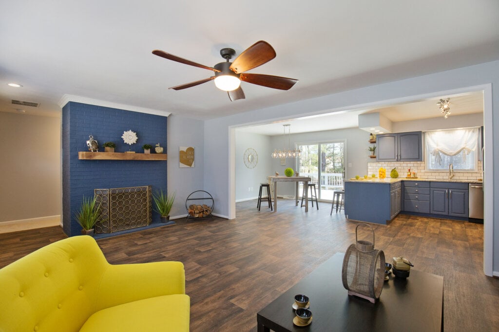 interior photo of a living room and kitchen with wood floors and bright yellow sofa.