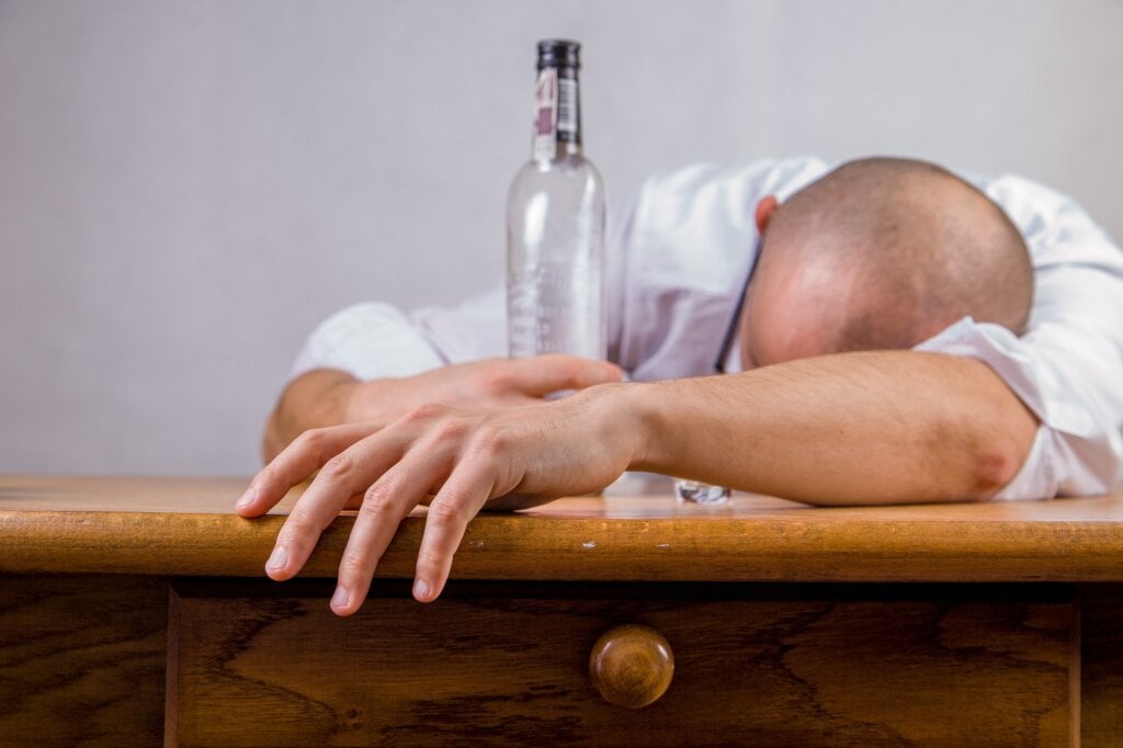 Man passed out on table with a bottle of liquor. - HomeJab