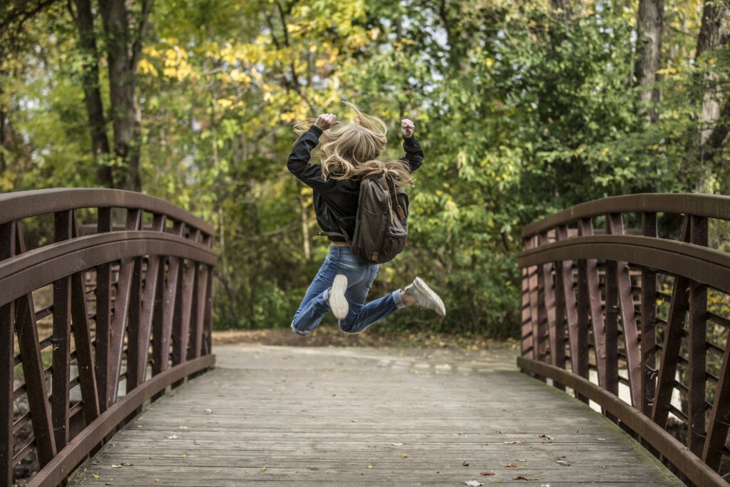 Young school girl jumping on a bridge. - HomeJab