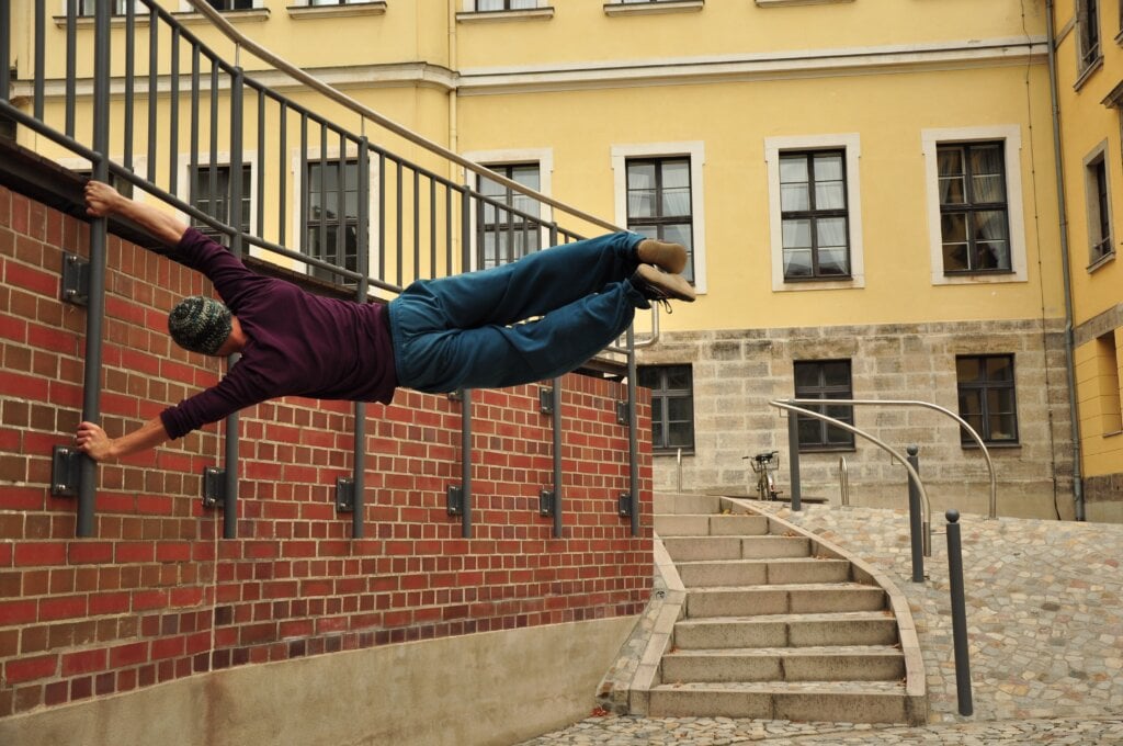 Man holding himself up horizontal, stretched out with his hands on the wall. - HomeJab