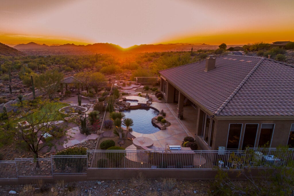 Areal drone photo of a home with a pool and large backyard at sunset. 