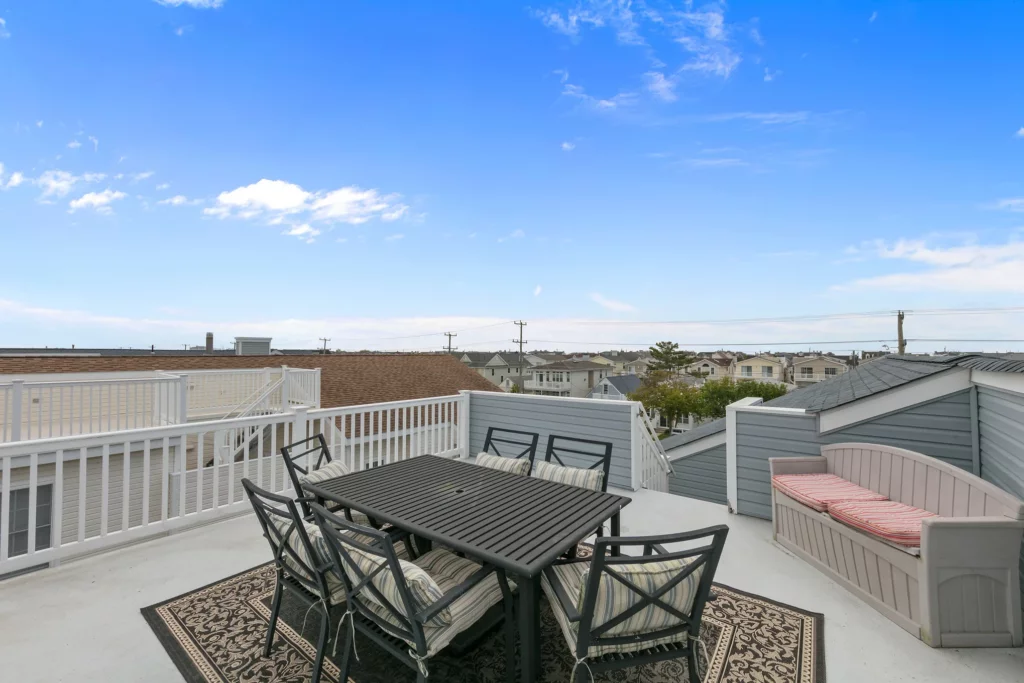 Roof top patio with table seating overlooking the neighborhood under a blue sky.