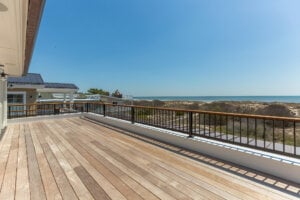 Outdoor photo of a wood patio deck and a view of the ocean in the distance.