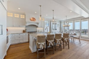 Large kitchen with white walls and cabinets, high ceilings and a bar area for dining. 