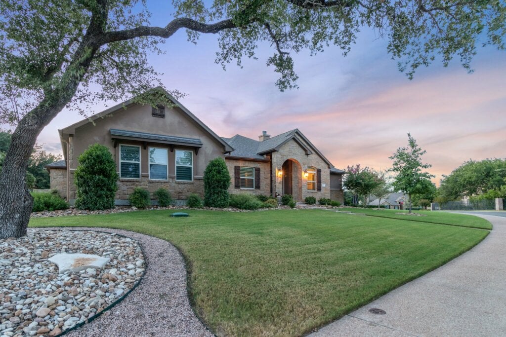 Curbside photo of a large home with a big front yard taken with a cloudy sky.