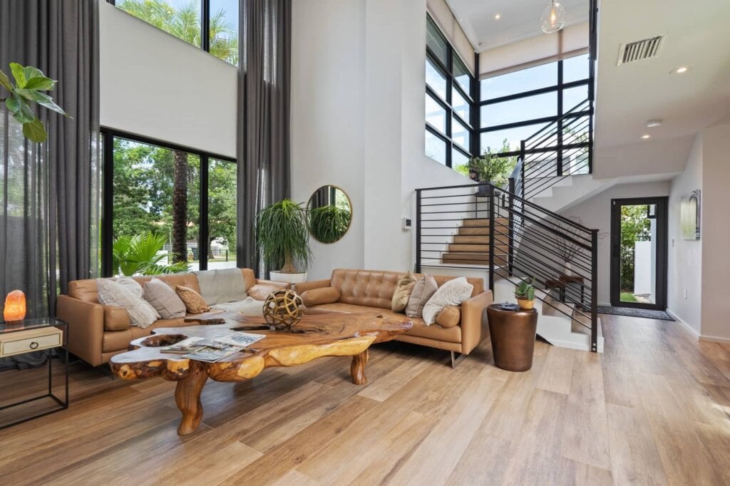 Large living room with high ceilings, white walls, wood floor and stairs.