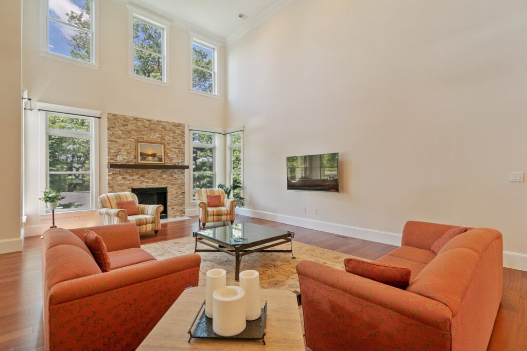 Large seating area with fire place, cream walls and orange sofa and accent chairs. - HomeJab