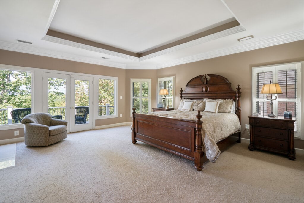 Spacious bedroom with beige walls and glass doors leading to the porch.