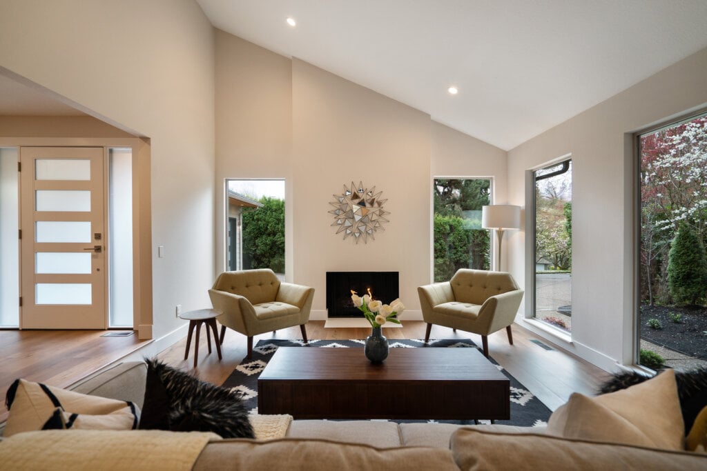 Beige livingroom with a wood floor, seating area and large windows. - HomeJab