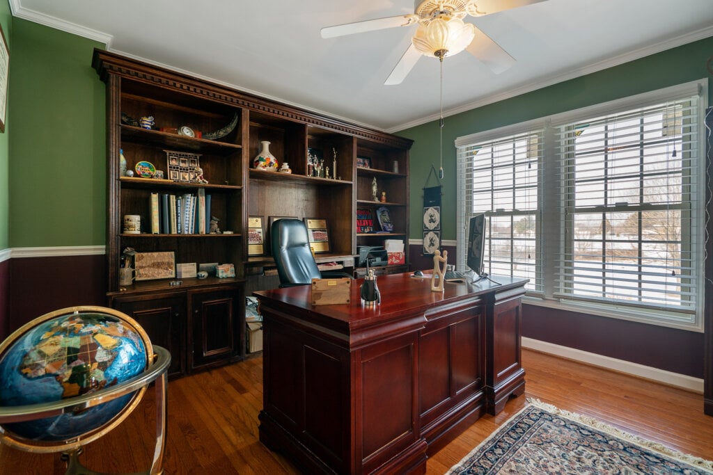 Large office with green walls, wooden book case and desk. - HomeJab