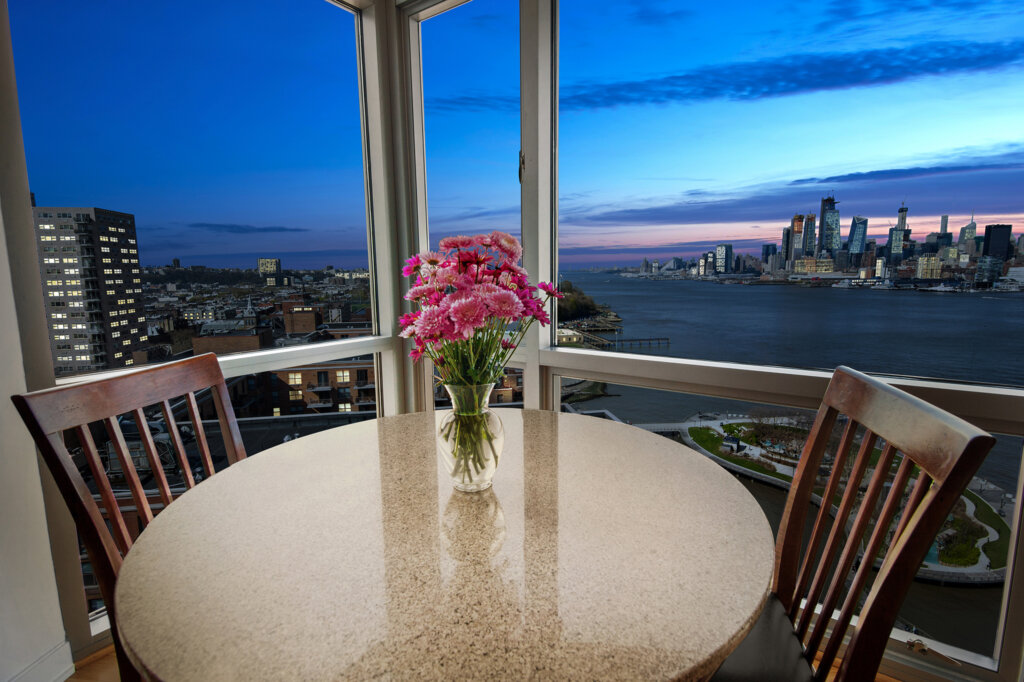 Dining table for two with a large picture window overlooking a bay.