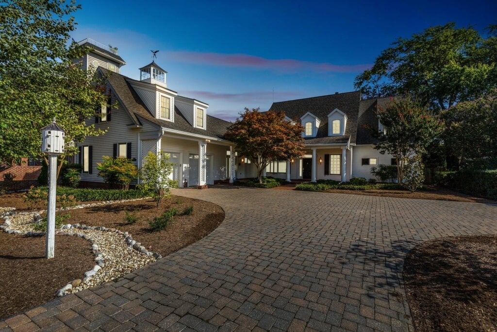 Two story house with white paneling and long driveway taken with twilight photography.