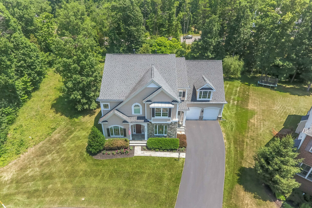 Areal drone photograph of a two story home with beige walls and white white trim.