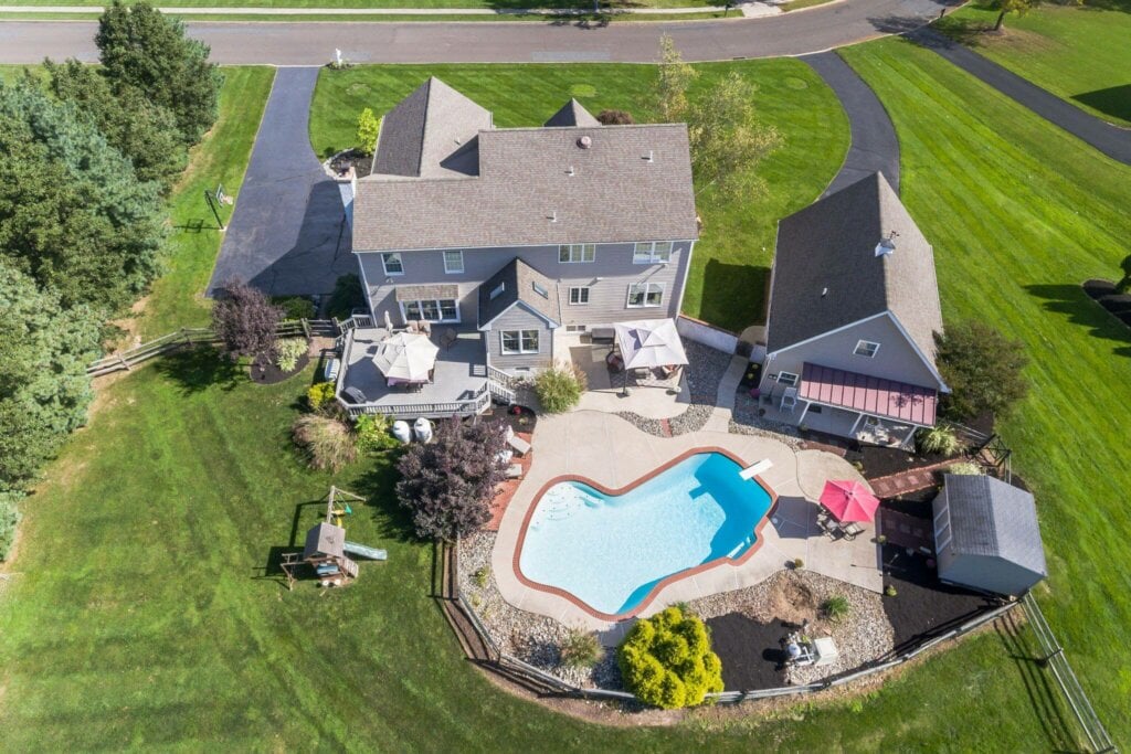 Areal photograph of a large real estate property with a two story house and pool.