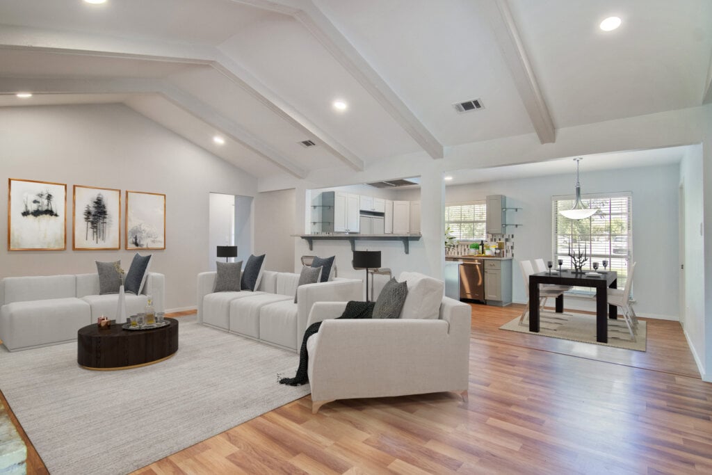 Large living room and dining room area with white walls and high ceiling.