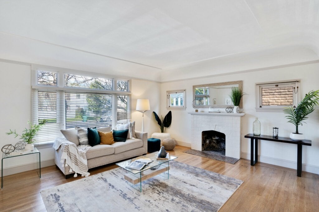 White living room with wood floor, rug and sofa with throw pillows - HomeJab