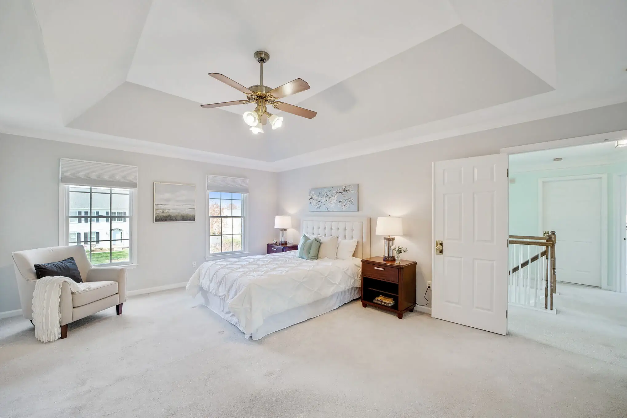 Large white bedroom with a ceiling fan in the center.