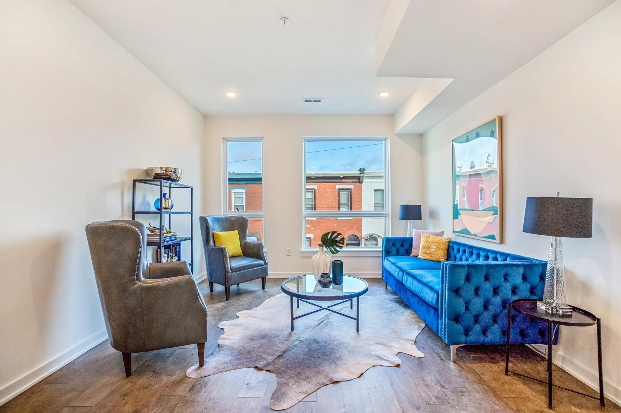 living room in a small apartment with a blue sofa and two accent chairs.