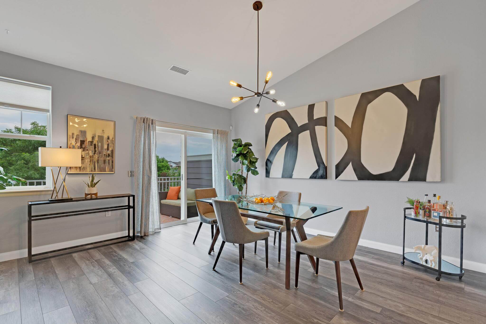 Large dining room with glass table and modern chairs, wood floor and art on the wall.