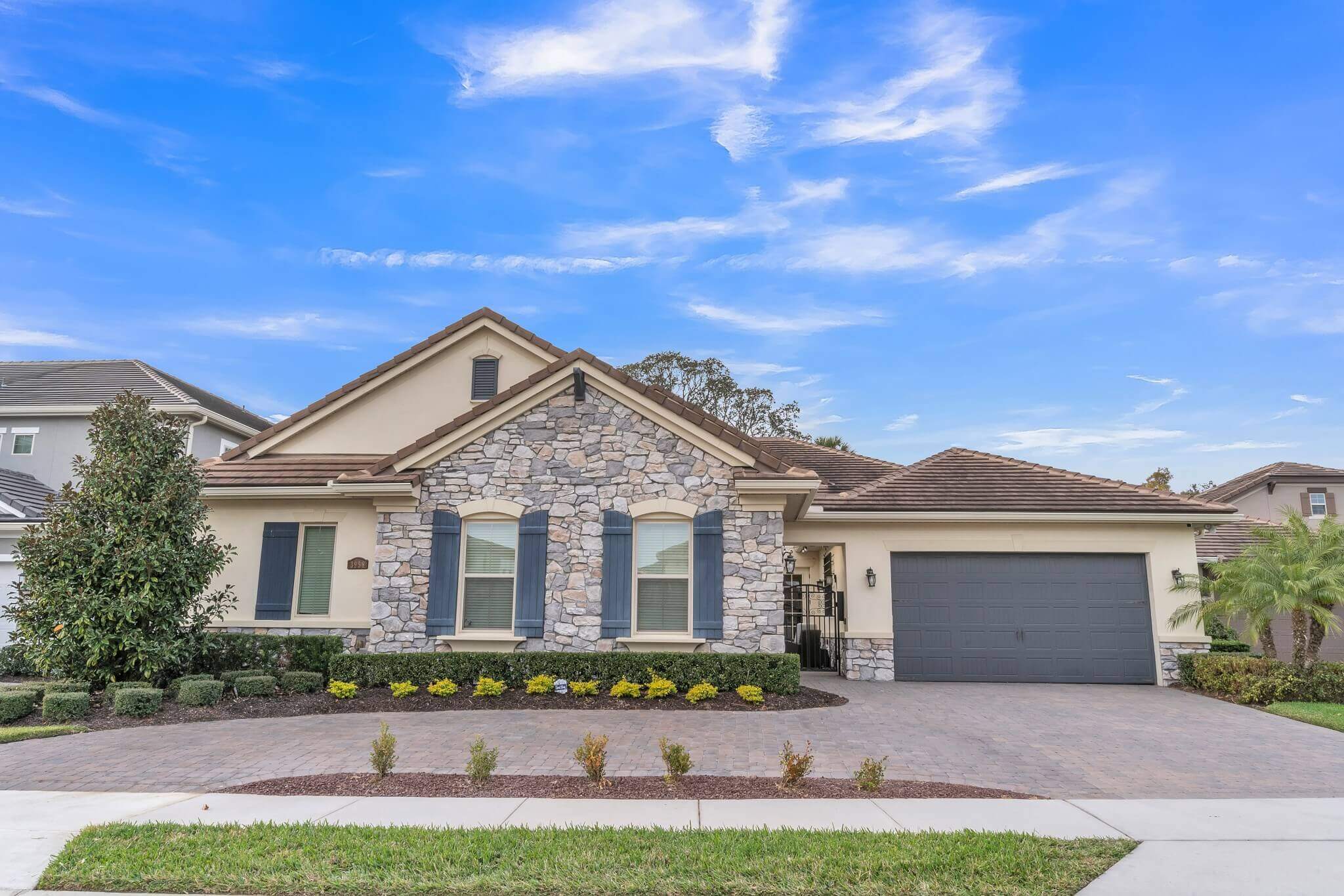 Curbside HDR photo of a home with cream colored walls with a rock front accent.